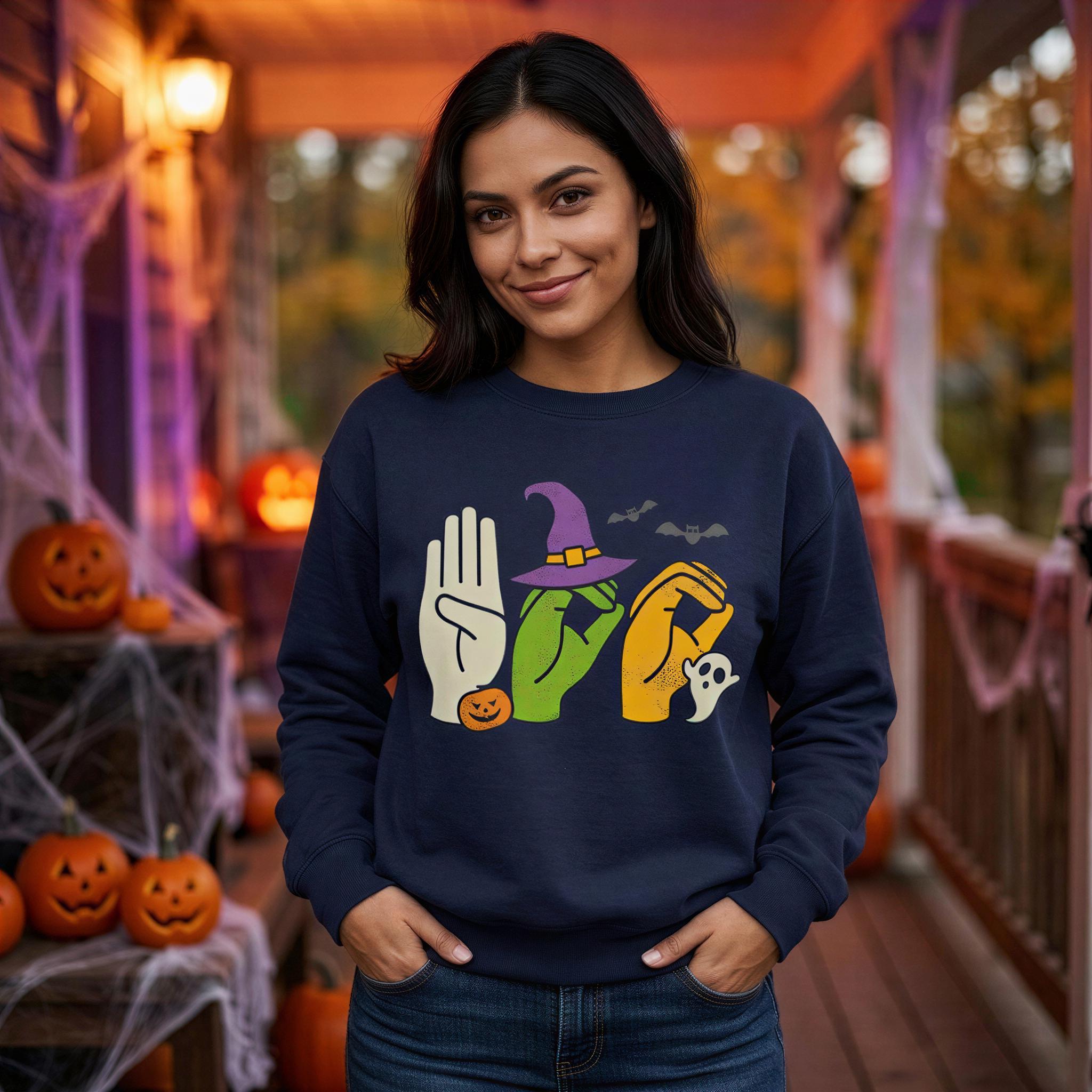A woman wearing a navy blue sweatshirt with a Halloween-themed graphic stands in front of a porch decorated for Halloween.