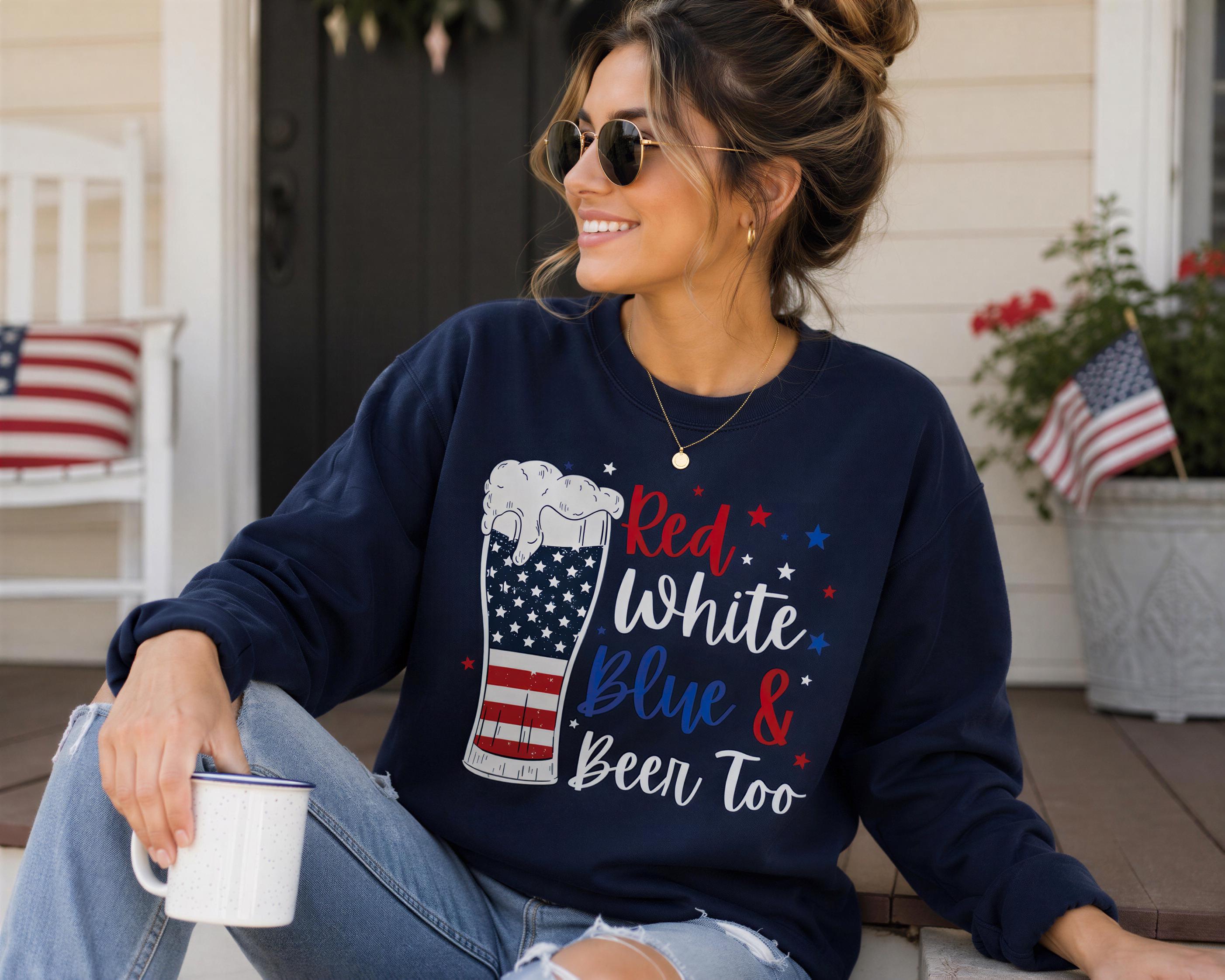 A woman wearing a navy blue sweatshirt with a graphic of a beer mug and stars, sitting on a porch and holding a mug.