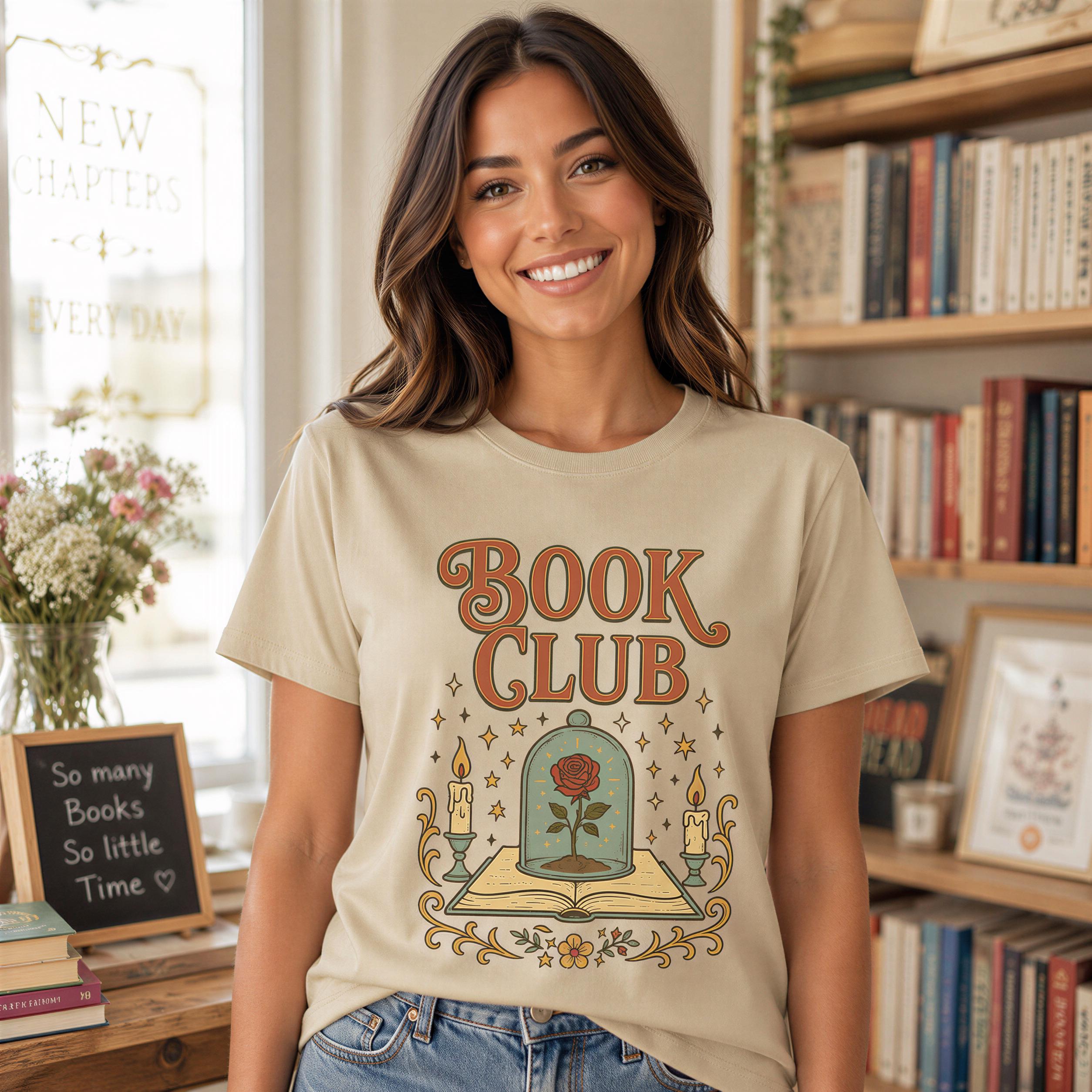 A smiling woman wearing a t-shirt with a graphic design of a book and a rose, standing in front of a bookshelf.