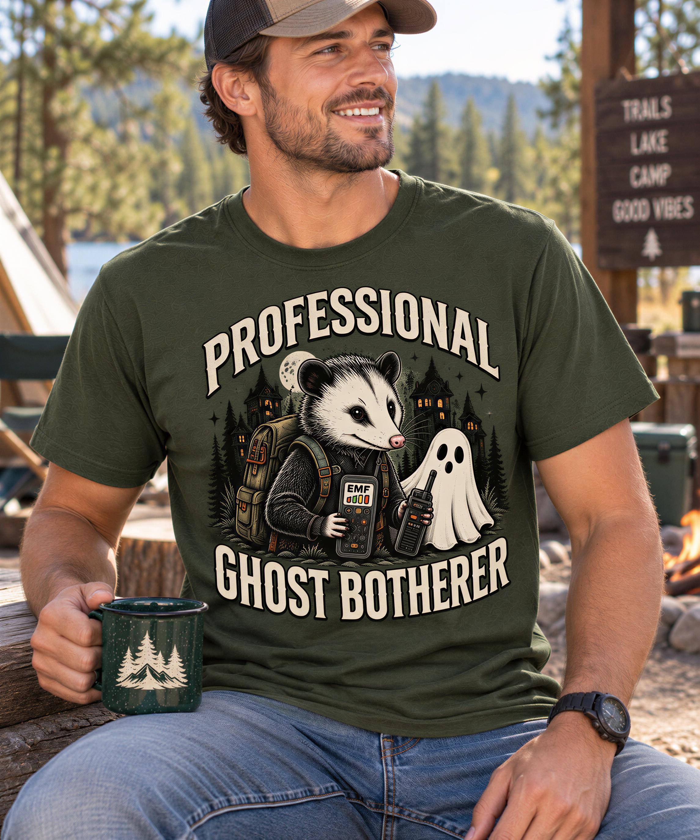 A man wearing a green t-shirt with a graphic design of a ghost character and the text "Professional Ghost Botherer" is sitting outdoors.