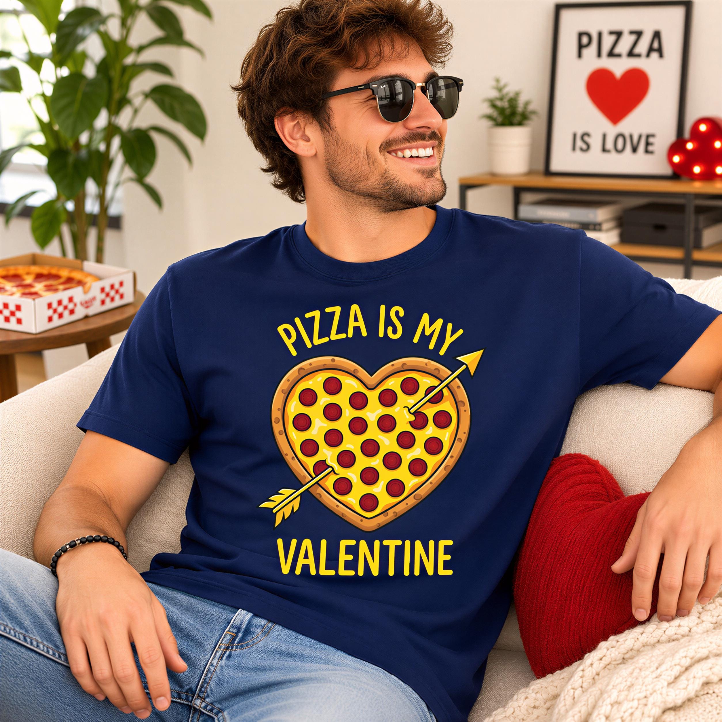 A man wearing a blue t-shirt with a heart-shaped pizza graphic and the text "Pizza is my Valentine" is sitting on a couch.