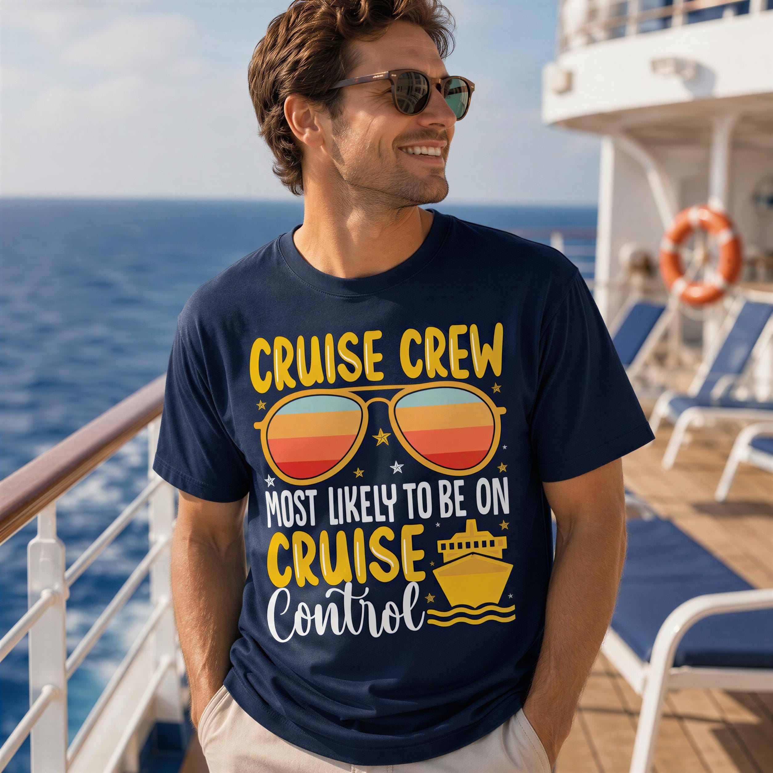 A man wearing a blue t-shirt with a graphic design and text on it, standing on a cruise ship deck.