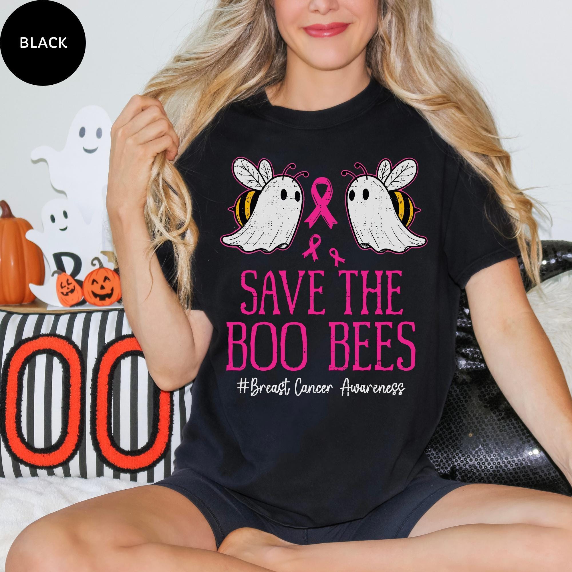 A woman wearing a black t-shirt with a graphic design featuring two ghostly bees and a pink ribbon, along with the text "Save the Boo bees #BreastCancerAwareness".