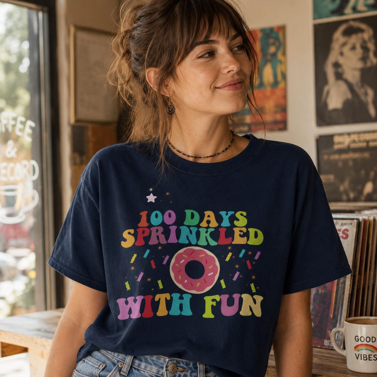 A woman wearing a navy blue t-shirt with a colorful graphic design and text, smiling and looking to the side.