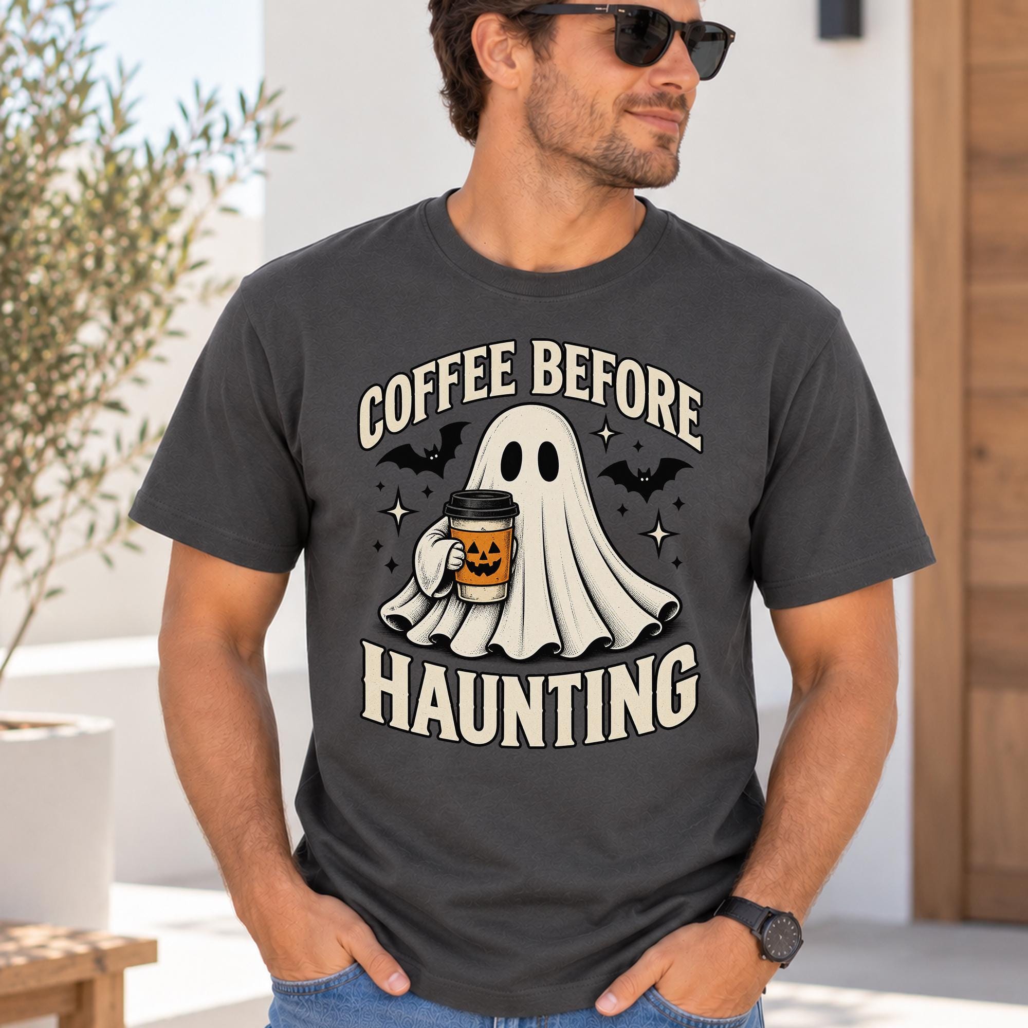 A man wearing a t-shirt with a graphic design of a ghost holding a coffee cup and the text "COFFEE BEFORE HAUNTING" printed on it.