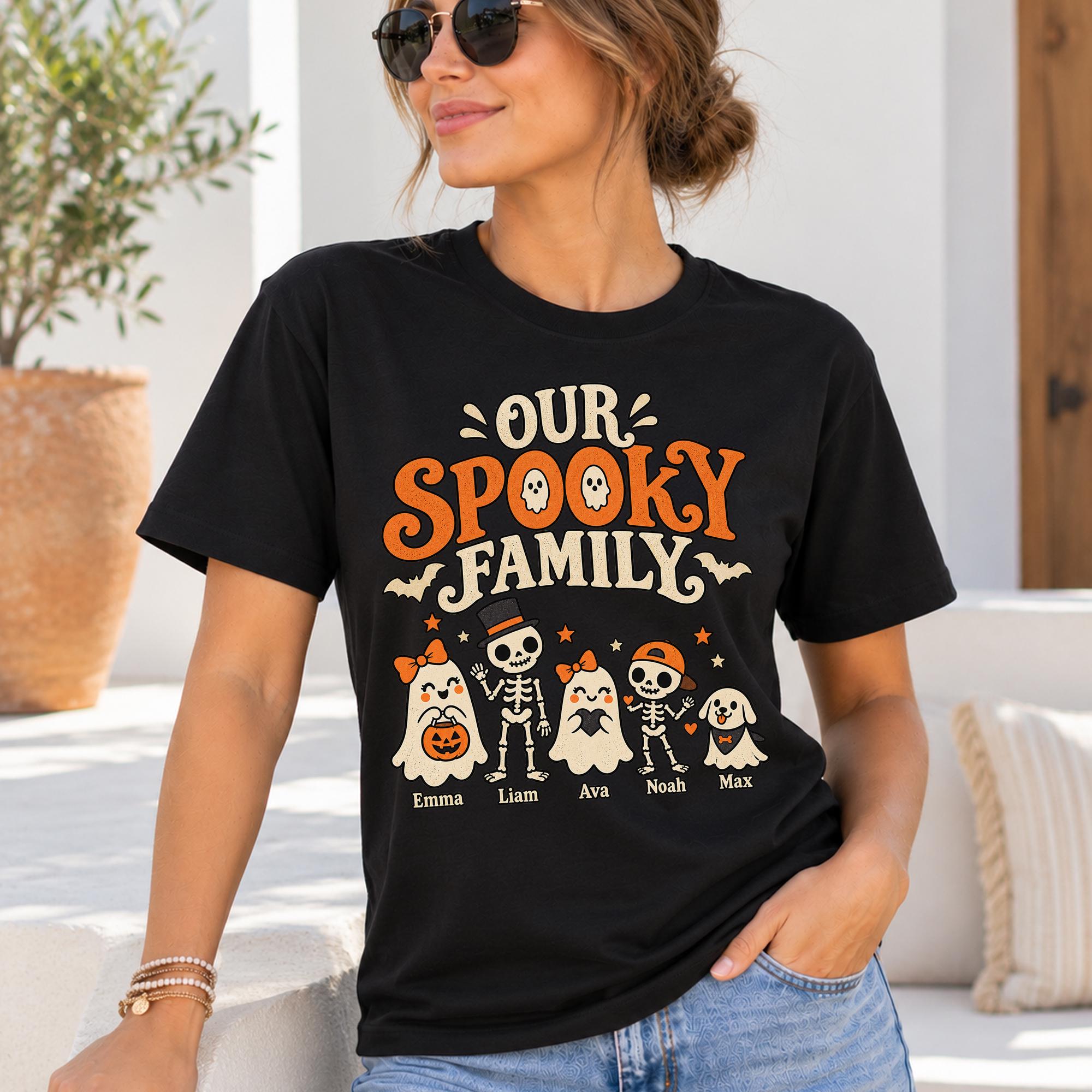 A woman wearing a black t-shirt with a Halloween-themed design, including a skeleton, ghost, and pumpkin.
