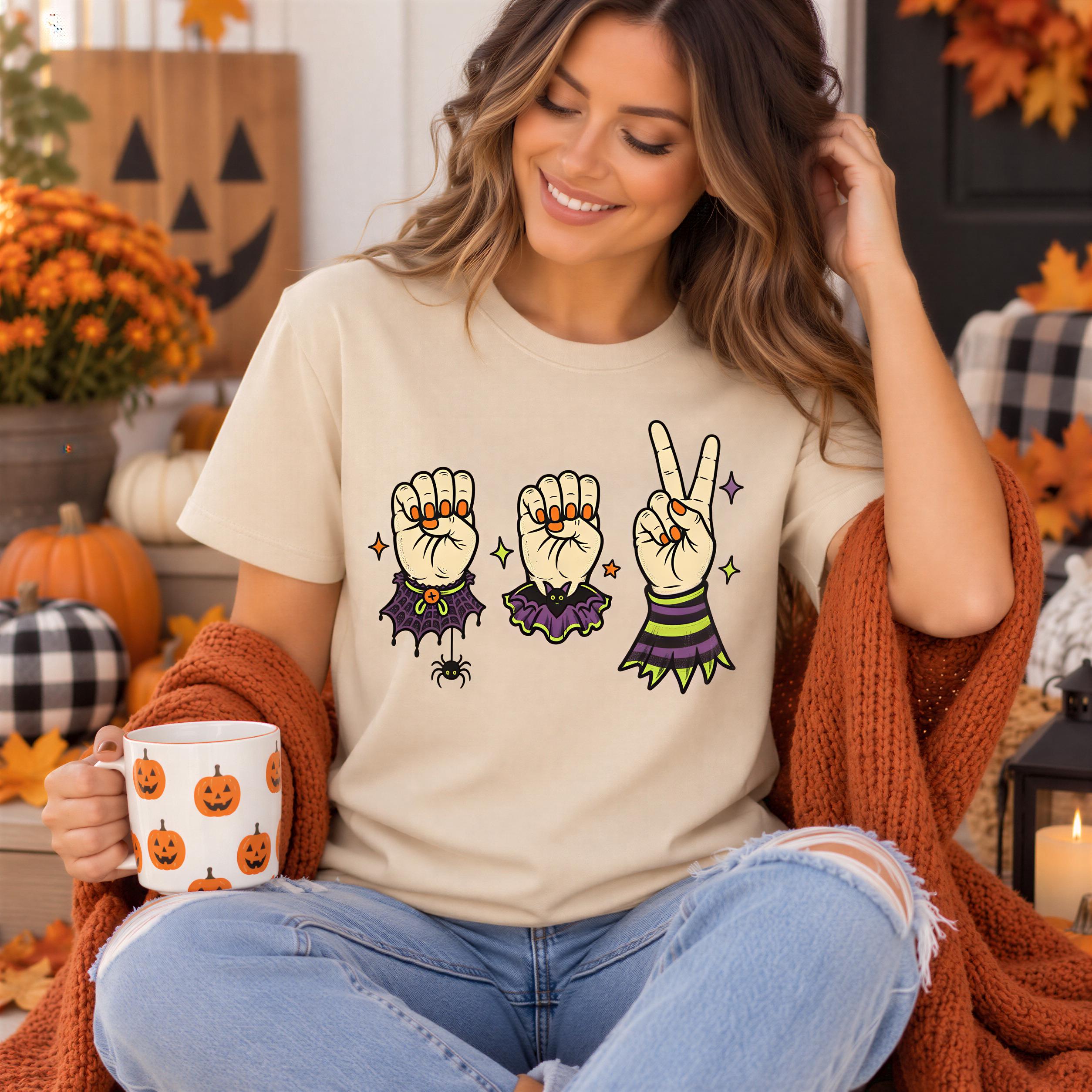 A woman wearing a t-shirt with a graphic design of three raised fists and a spider, sitting on a porch surrounded by Halloween decorations.