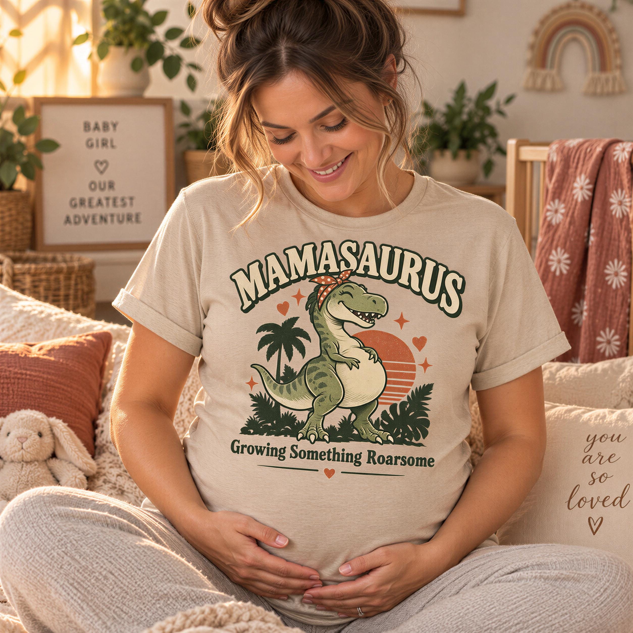 A pregnant woman wearing a t-shirt with a graphic of a dinosaur and the text "Mamosaurus Growing Something Roarsome" is sitting on a bed surrounded by potted plants and a stuffed animal.