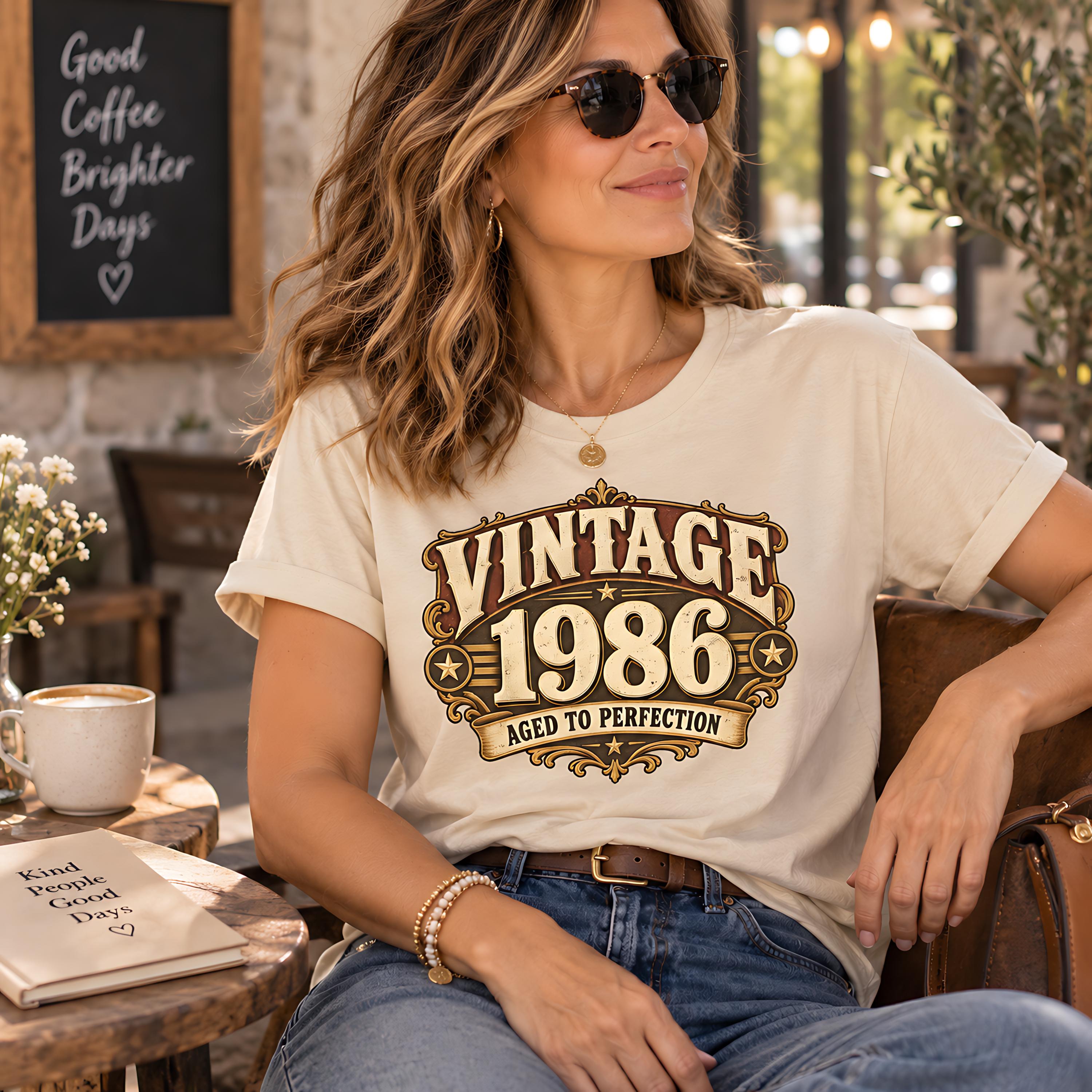 A woman wearing a white t-shirt with a vintage-style graphic and sunglasses is sitting at a table in a cafe.