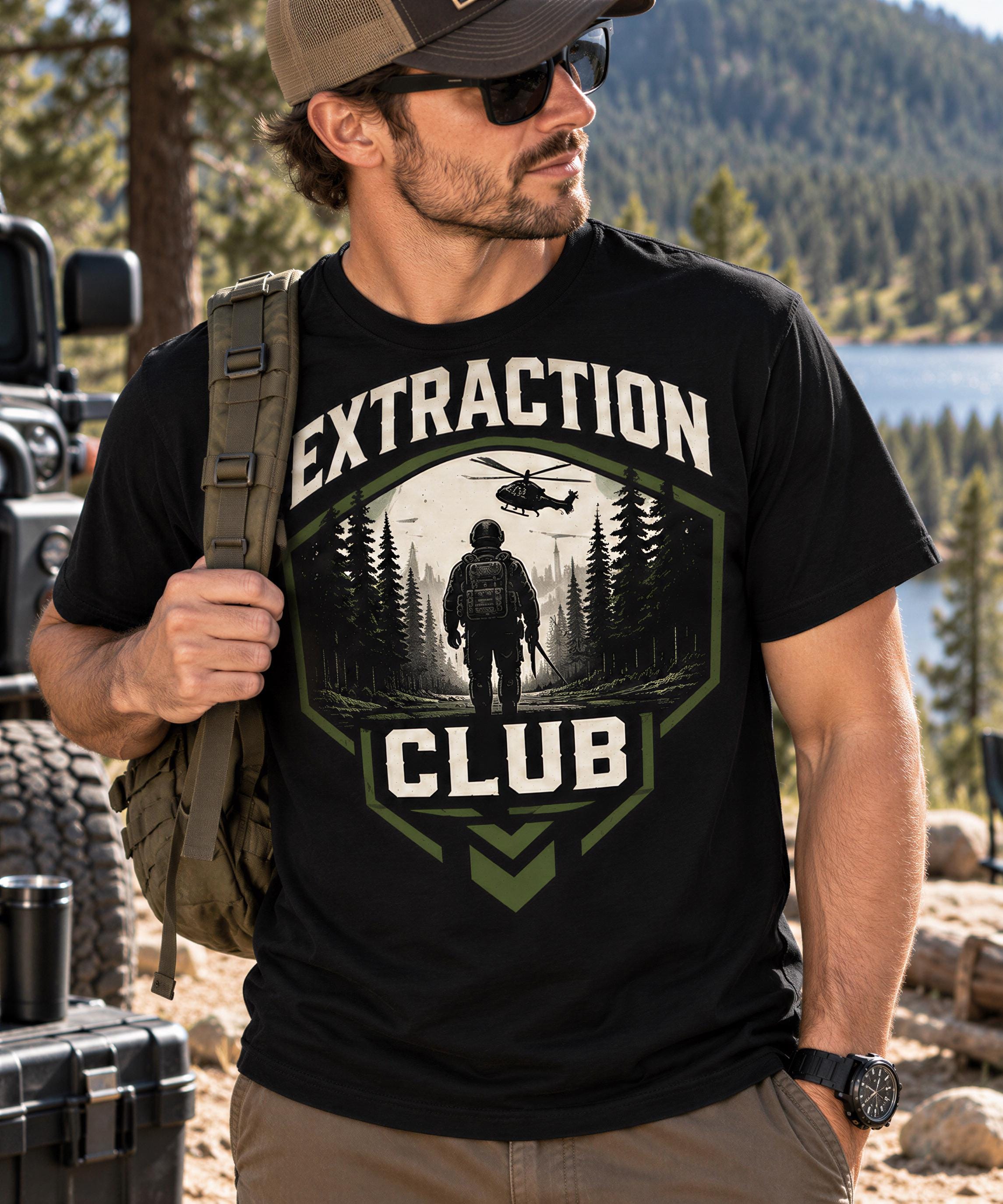 A man wearing a black t-shirt with a graphic design of a soldier and a helicopter, standing in a forest setting.