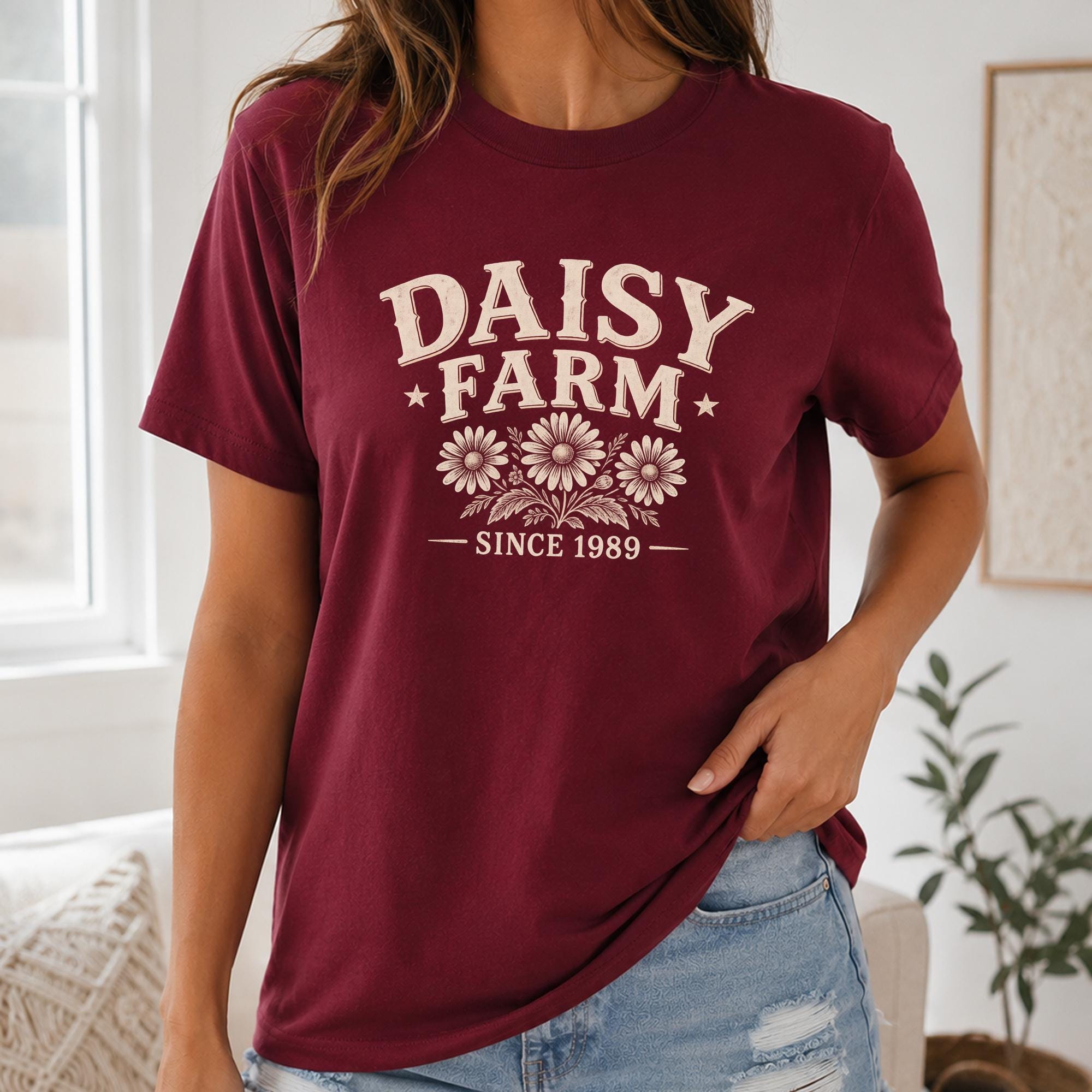 A woman wearing a burgundy t-shirt with the text "DAISY FARM SINCE 1989" printed on it.