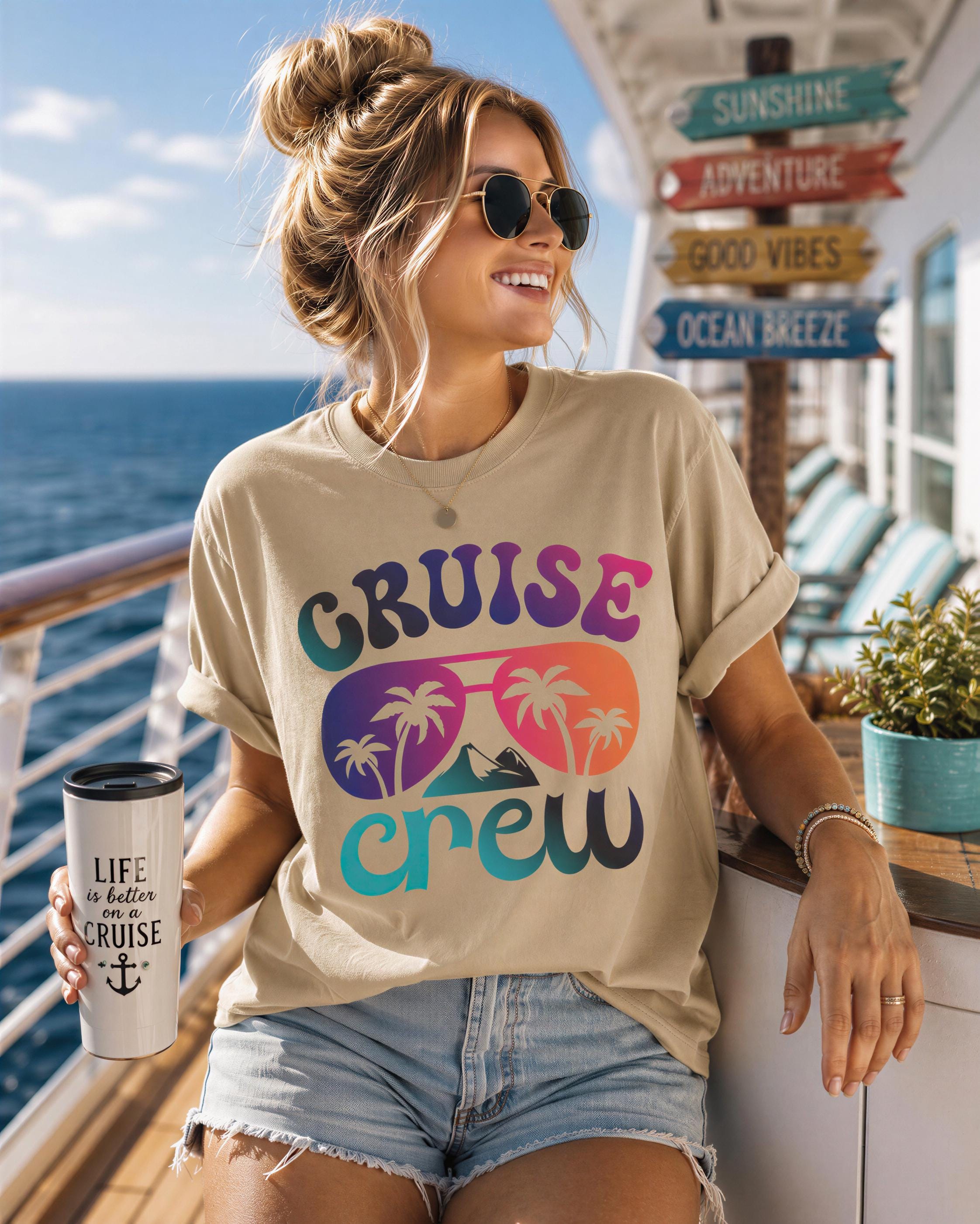 A woman wearing sunglasses and a t-shirt with a cruise crew graphic is standing on a cruise ship deck, holding a drink.