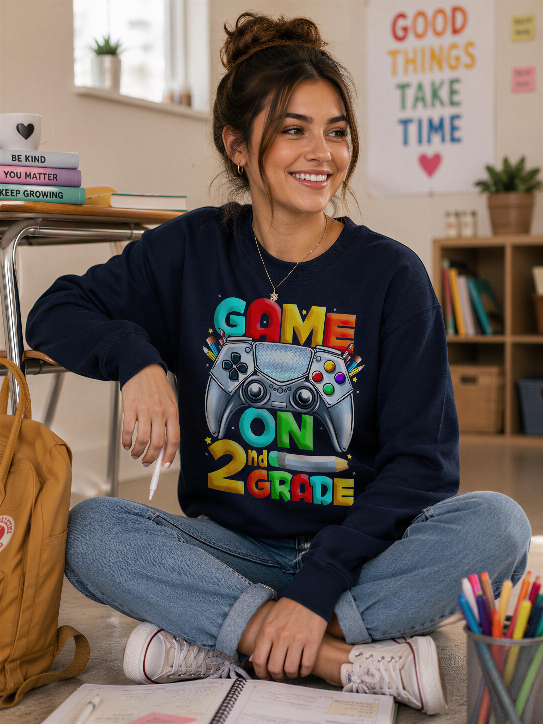 A young woman sitting on the floor, wearing a sweatshirt with a colorful graphic and text, smiling and holding a pen.