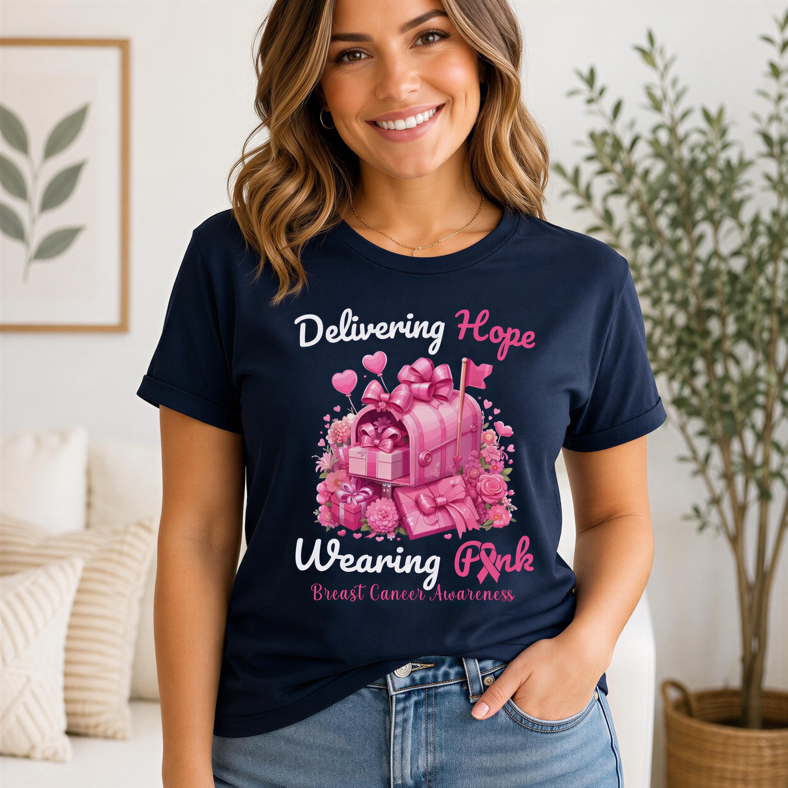 A woman wearing a navy blue t-shirt with a pink graphic design and text related to breast cancer awareness.