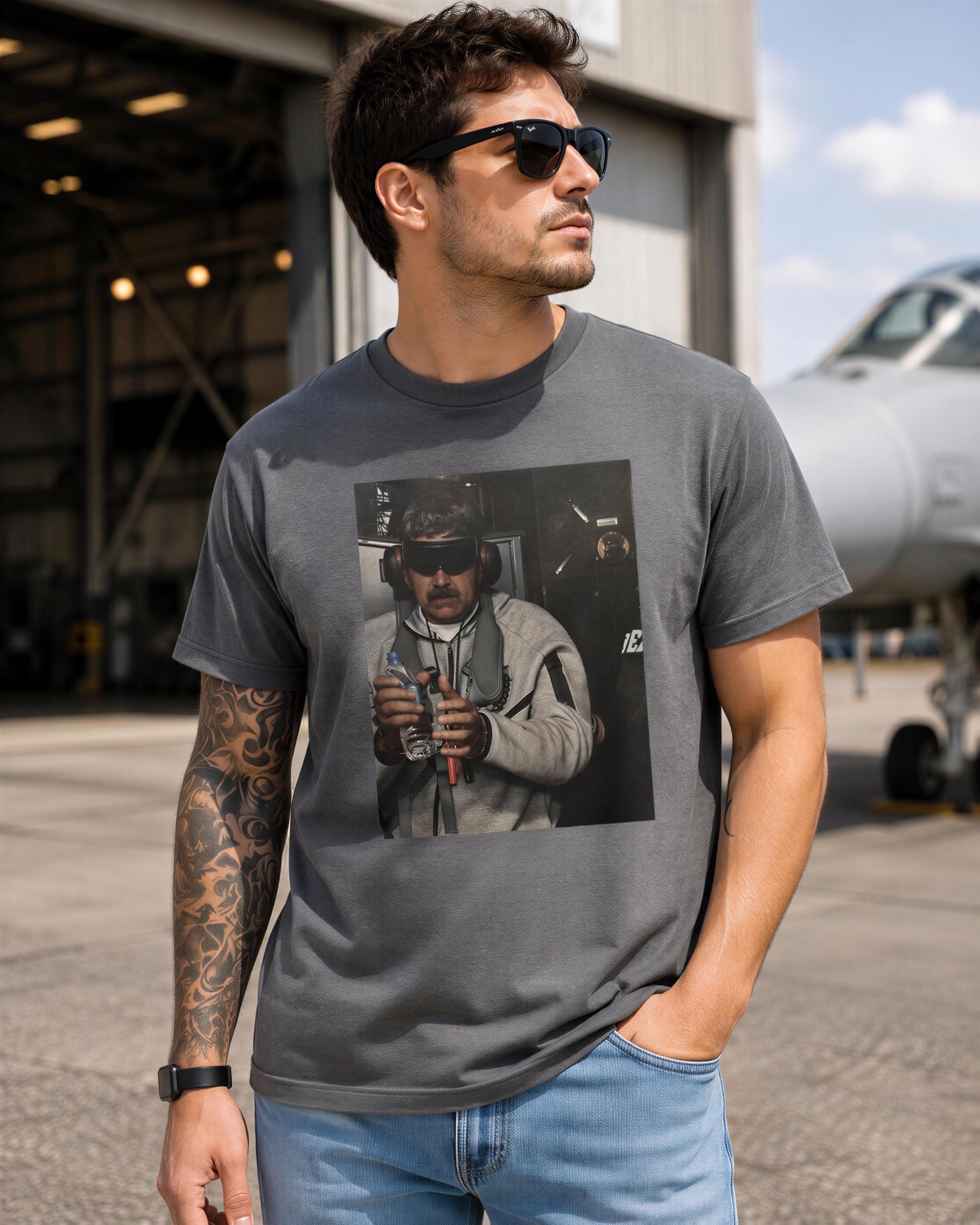 A man wearing sunglasses and a t-shirt with a graphic of a man in a helmet is standing in front of a large airplane.