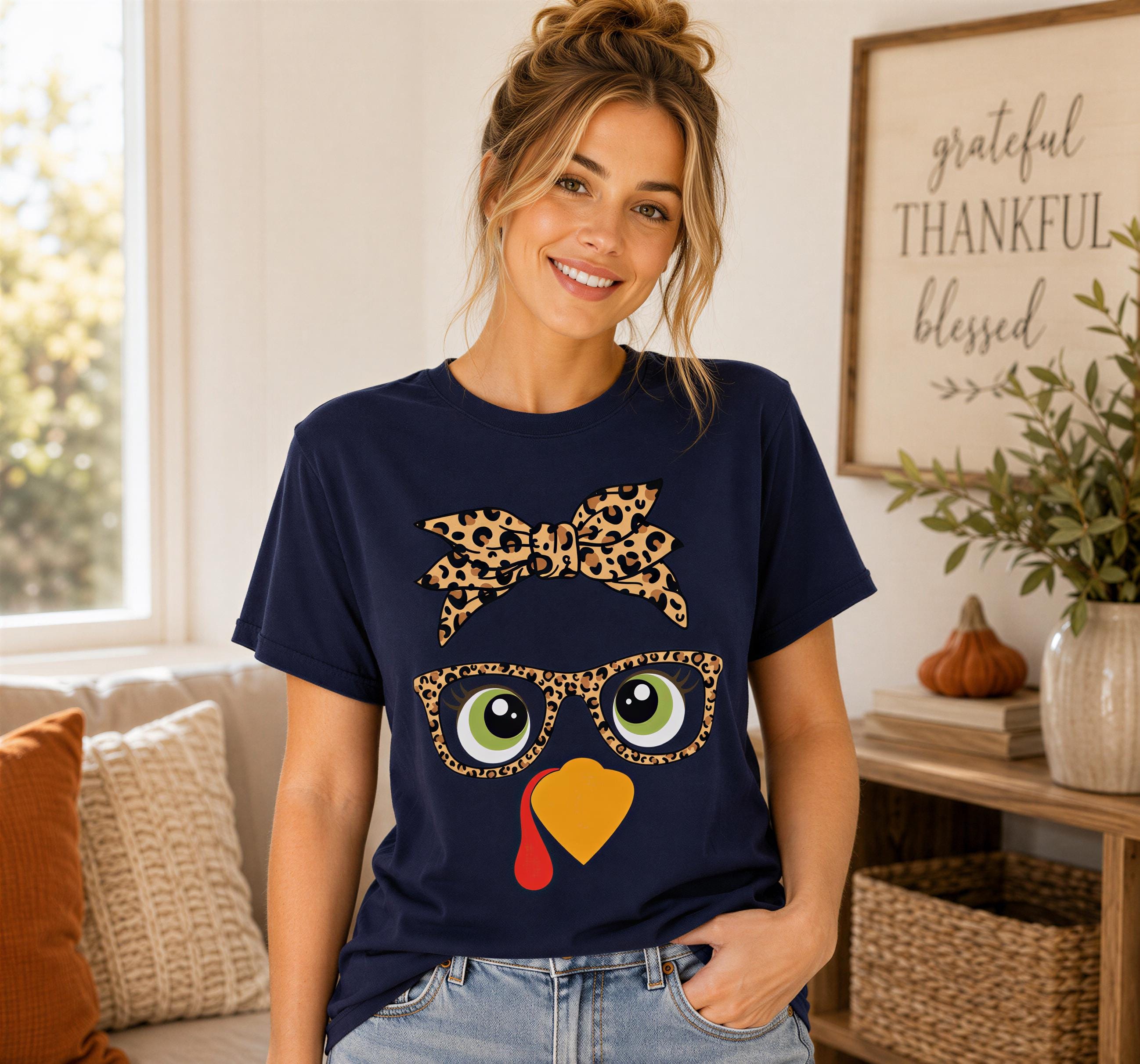A woman wearing a navy blue t-shirt with a leopard print bow and a turkey face design, smiling at the camera.