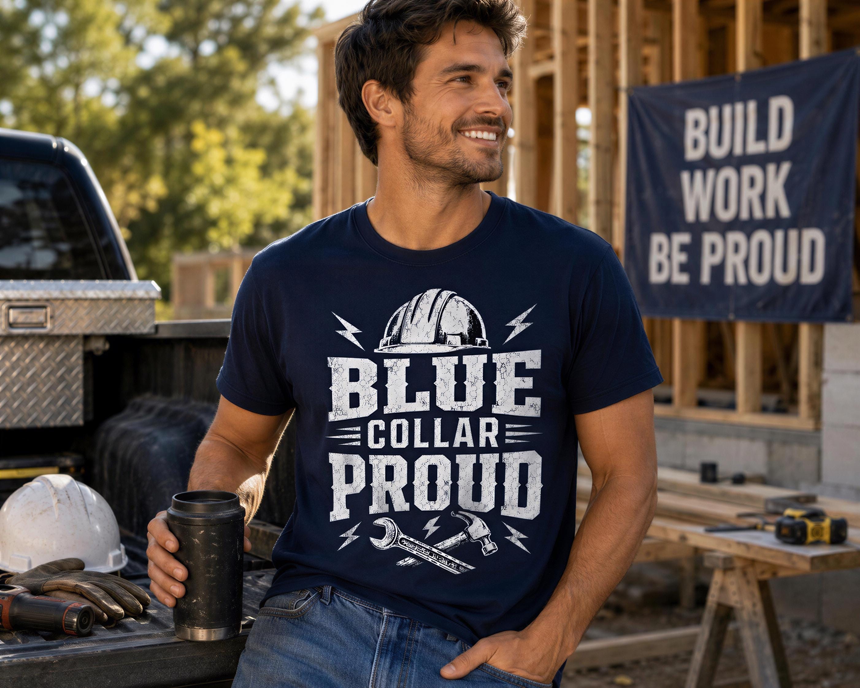 A man wearing a blue t-shirt with the text "BLUE COLLAR PROUD" is sitting in a truck bed, smiling, with a construction site and a "BUILD WORK BE Proud" banner visible in the background.