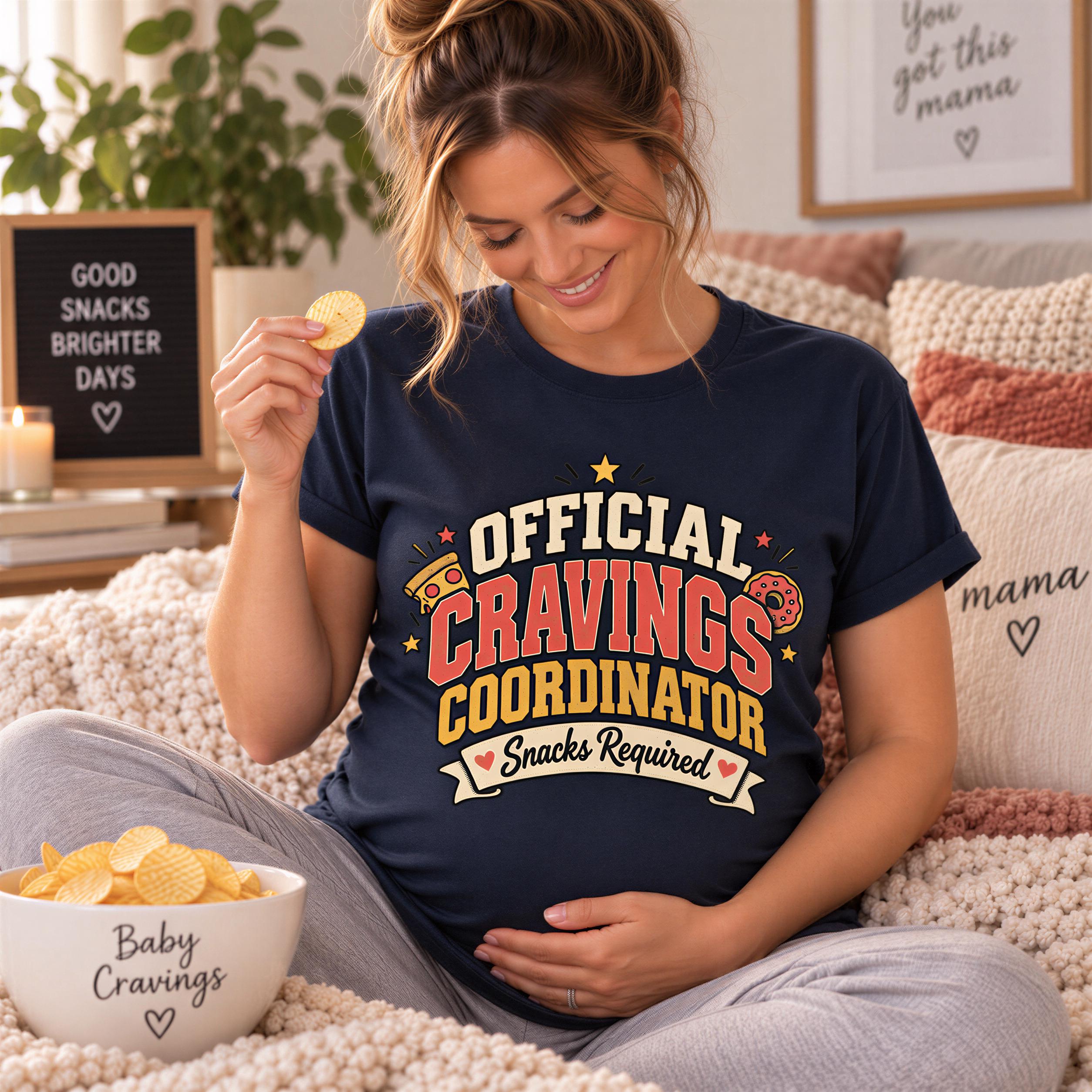 A pregnant woman wearing a blue t-shirt with a humorous text and holding a snack, sitting on a bed with a bowl of chips and a sign that says "Good snacks brighter days".