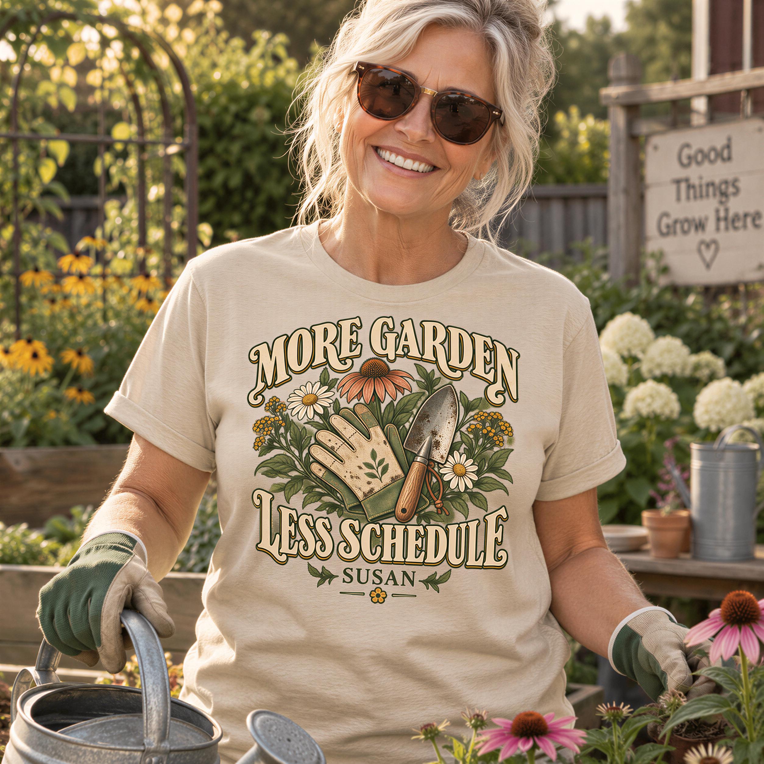 A smiling woman wearing a t-shirt with a graphic design of gardening tools and flowers, standing in a garden surrounded by flowers and plants.