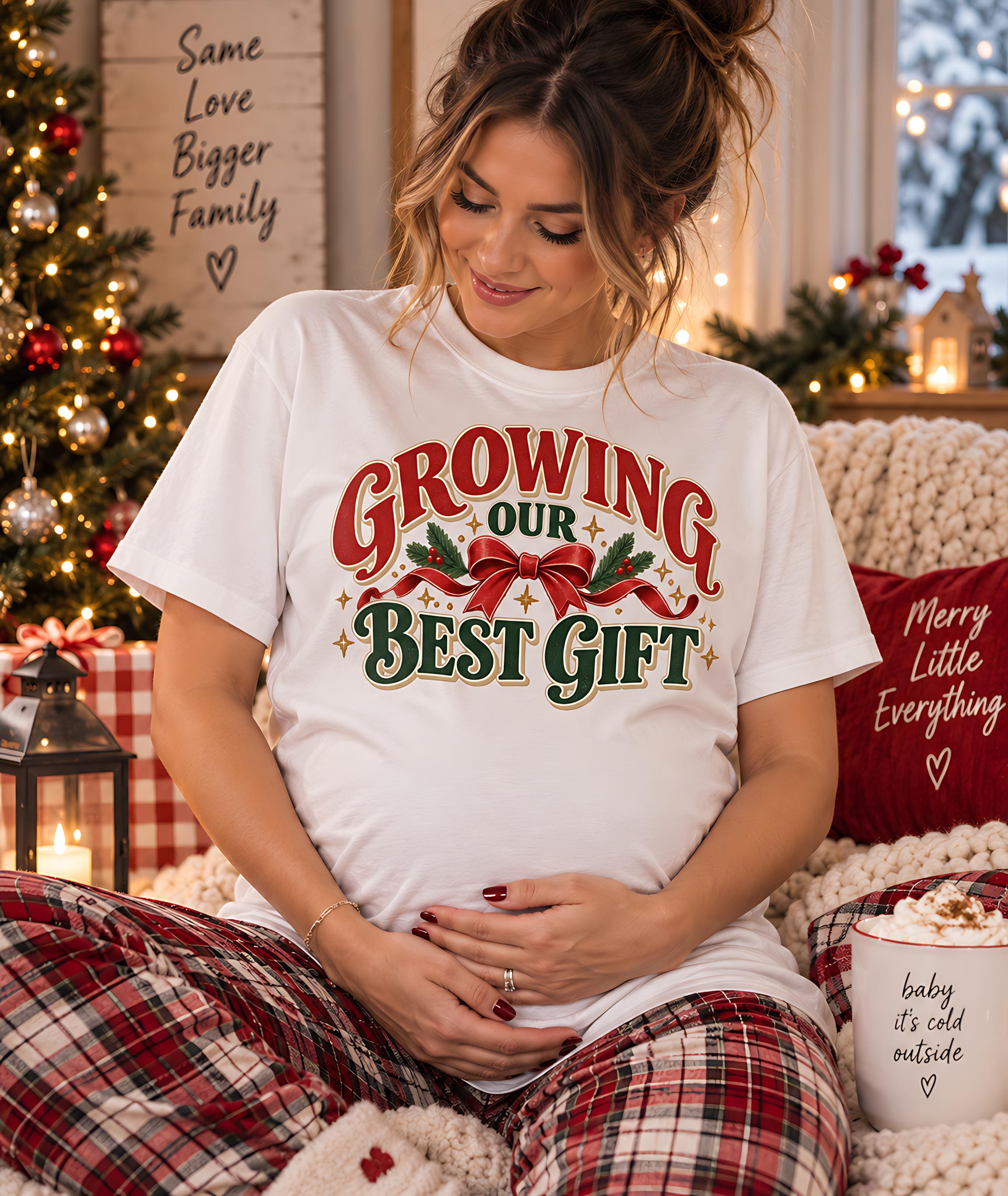 A pregnant woman wearing a white t-shirt with the text " Growing our best gift" is sitting on a couch, smiling and holding her hands together.