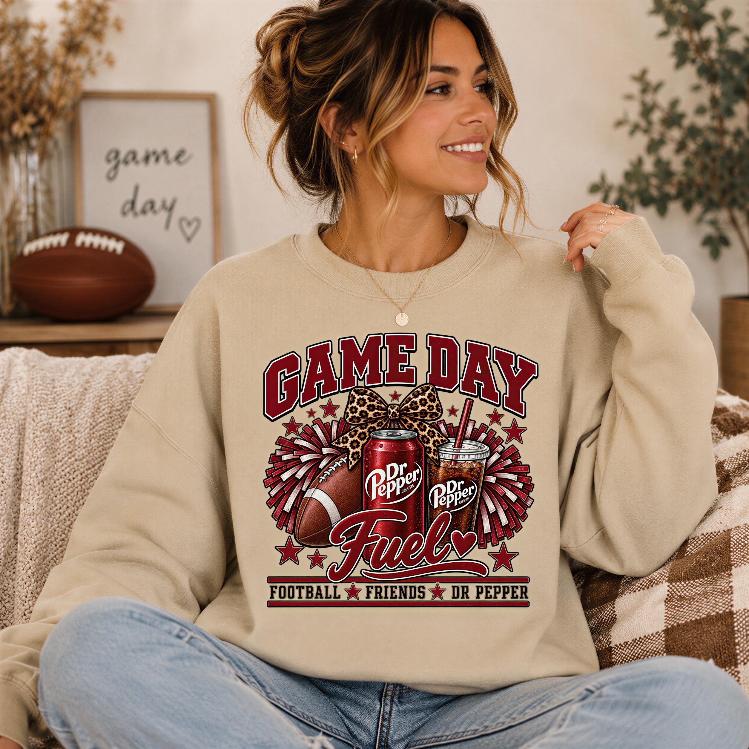 A woman wearing a beige sweatshirt with a graphic design of a football and a can of Dr Pepper, along with the text "Game Day Fuel" and "Dr Pepper".