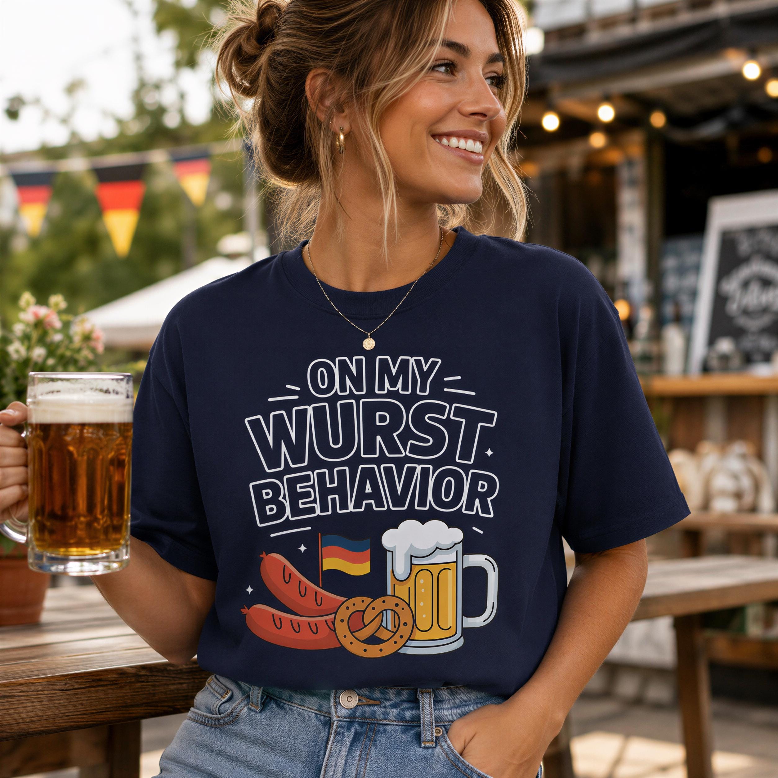 A woman wearing a navy blue t-shirt with a graphic design of hot dogs and beer, holding a glass of beer and smiling.