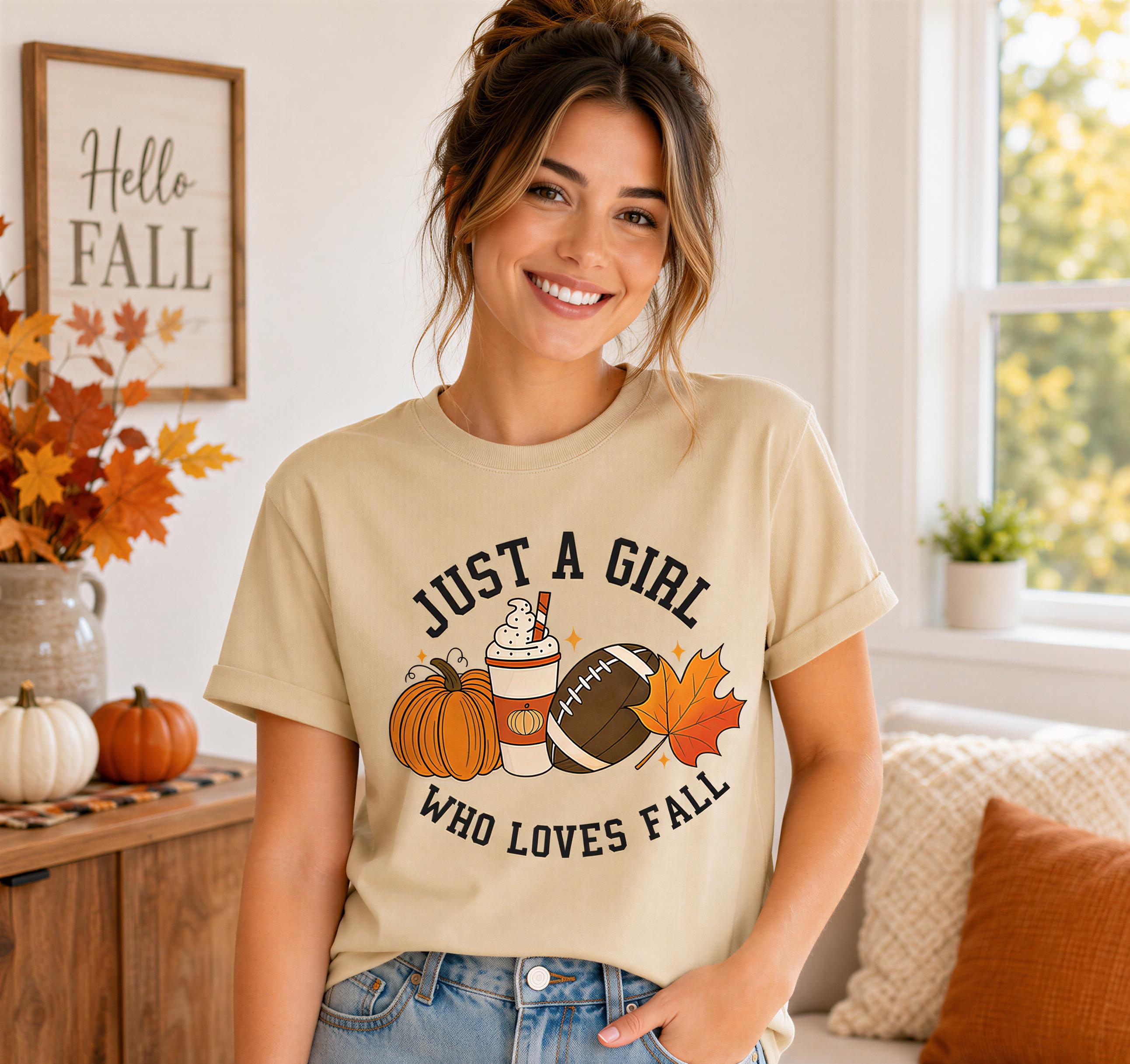 A woman wearing a t-shirt with a graphic design of a football, pumpkin, and a cup of coffee, smiling at the camera.