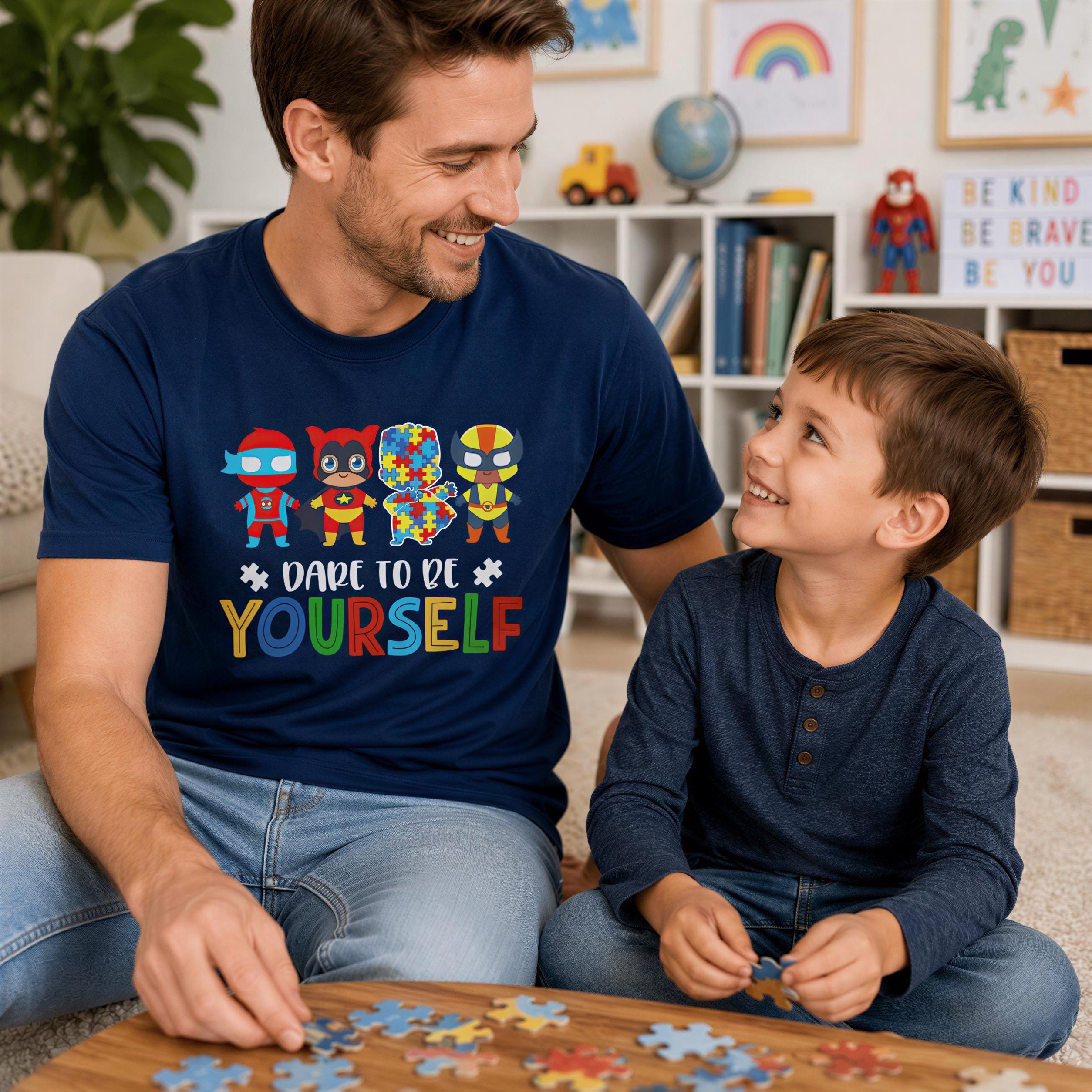 A man and a young boy are sitting together on the floor, smiling and working on a puzzle. The man is wearing a blue t-shirt with a colorful design, and the boy is wearing a blue shirt. They are surrounded by various toys and books, creating a playful and engaging environment.
