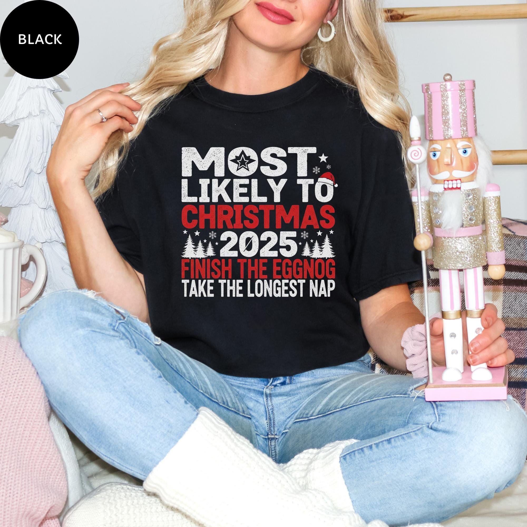 A woman wearing a black t-shirt with a humorous Christmas-themed text, sitting on a couch and holding a nutcracker.