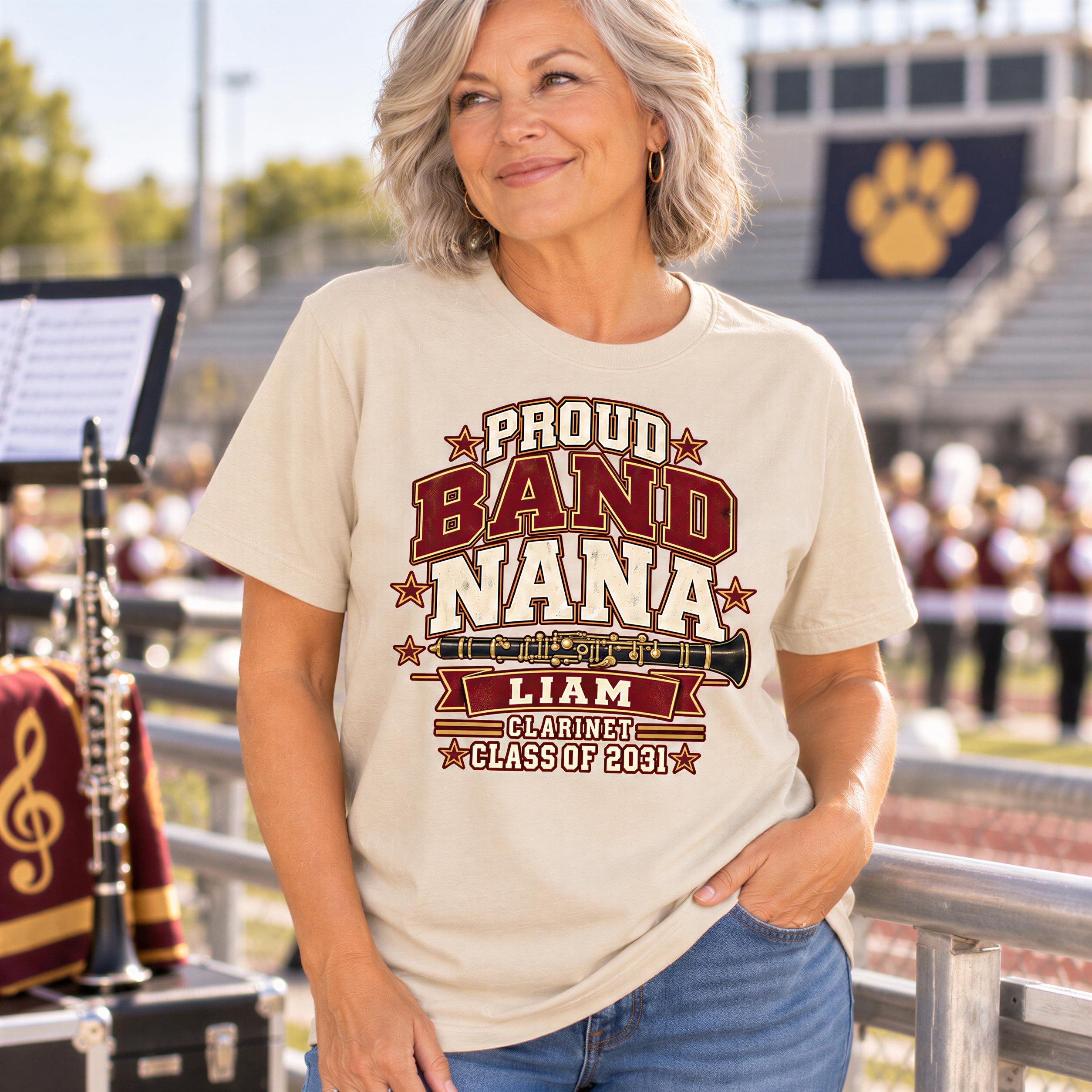 A woman wearing a t-shirt with a graphic design stands in front of a marching band, smiling.