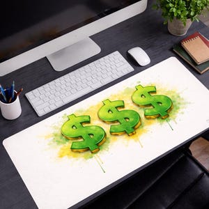 Puede incluir: Una alfombrilla de escritorio blanca con tres símbolos de dólar verdes y acentos de acuarela amarillos y verdes. La alfombrilla está sobre un escritorio negro con una computadora, teclado, ratón y otros suministros de oficina.