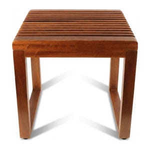 Puede incluir: Un pequeño taburete cuadrado de madera con una parte superior de listones y cuatro patas resistentes. El taburete está hecho de madera de tonos cálidos, probablemente caoba o teca, y tiene un diseño simple y minimalista. El taburete mide aproximadamente 46 cm de alto.