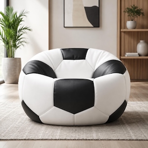 May include: A large, round beanbag chair designed to resemble a soccer ball. The chair features a pattern of white and black pentagons, with a soft, cushioned appearance. The chair is placed on a neutral-colored rug.