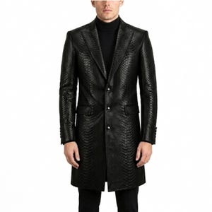 May include: A black long coat featuring a textured snakeskin pattern, a notched lapel, and a three-button front closure. The coat is worn over a black turtleneck jumper, showcasing long sleeves with buttoned cuffs and two side flap pockets.
