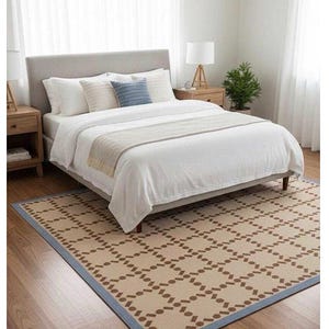 Puede incluir: Una habitaci&oacute;n con una cama con ropa de cama blanca, almohadas y un cabecero gris. Una alfombra estampada con un borde azul y una mesita de noche de madera con una l&aacute;mpara est&aacute;n en la habitaci&oacute;n. Una peque&ntilde;a planta est&aacute; en la mesita de noche.