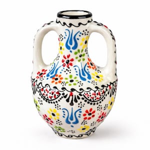 Könnte beinhalten: Kleine, weiße Keramikvase mit zwei Henkeln, verziert mit bunten Blumen- und geometrischen Mustern. Die Vase hat rote, blaue, gelbe und grüne Akzente, mit einem schwarzen Rand und Boden. Ein dekoratives Stück.