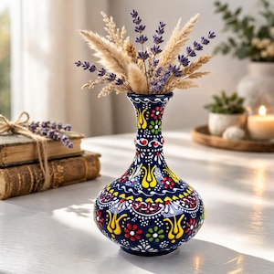 Könnte beinhalten: Eine marineblaue Keramikvase mit farbenfrohem Blumenmuster, gefüllt mit getrocknetem Lavendel und Weizenähren. Die Vase hat einen bauchigen Körper und einen schlanken Hals. Die Vase ist etwa 20 cm hoch.