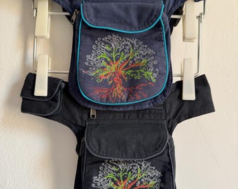 Puede incluir: Dos riñoneras utilitarias con un diseño de árbol bordado en la solapa frontal. La bolsa superior es azul marino con ribetes azul brillante, mientras que la inferior es negra con ribetes grises. Ambas incluyen un compartimento principal con cremallera y un bolsillo lateral.