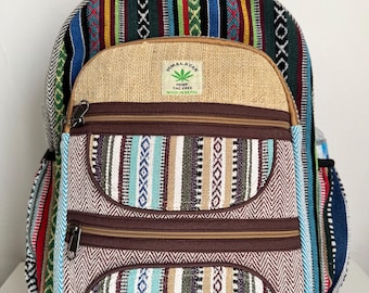 Puede incluir: Una mochila colorida con un panel frontal de tela de cáñamo y múltiples bolsillos con cremallera. La bolsa presenta una variedad de patrones tejidos en tonos de azul, verde, rojo y marrón. El texto "Himalayan Hemp THC Free Made in Nepal" es visible.