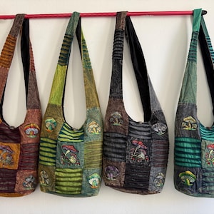 Può includere: Quattro borse a tracolla stile hobo appese in fila, ognuna caratterizzata da un design patchwork con varie tonalità di tessuto marrone, verde e nero. Ogni borsa è decorata con motivi a fungo ricamati e spallacci in tessuto arricciato.