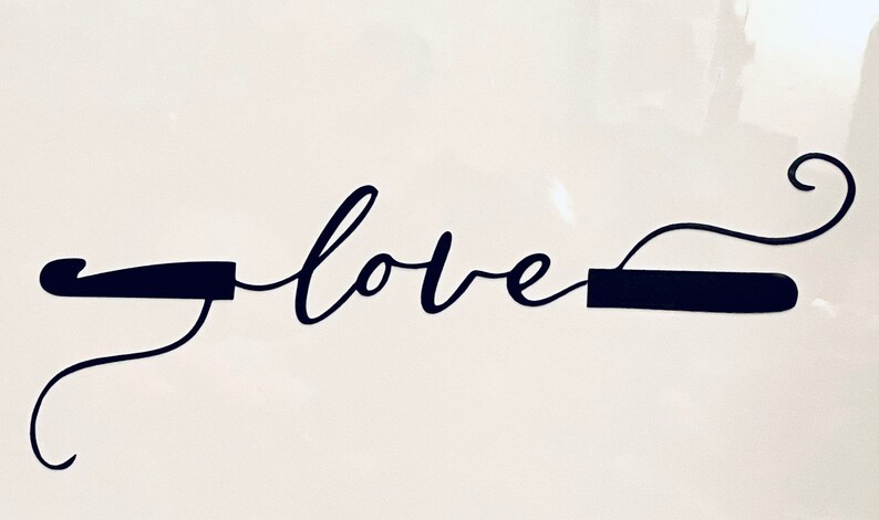 May include: A black cursive "love" word art design. The word is flanked by two dark rectangular shapes with curved lines extending from each end. The design is set against a white background.