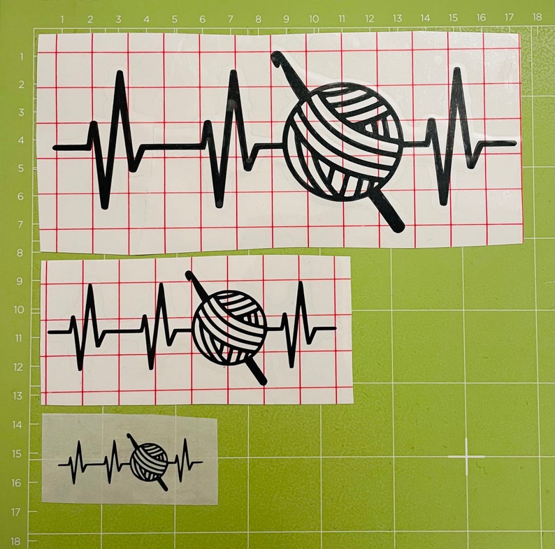 May include: Black vinyl decals featuring a heartbeat design with a yarn ball and crochet hook. The decals are in three sizes, perfect for crafting projects. The design is a creative representation of a crocheter's passion.