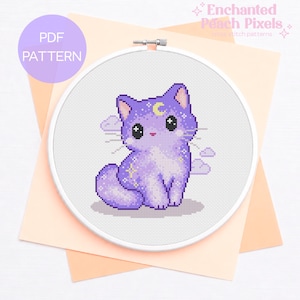 Può includere: Un modello a punto croce con un gatto viola con una luna crescente e stelle. Il gatto è circondato da nuvole ed è all'interno di un telaio da ricamo bianco. Le parole "PDF PATTERN" sono in un cerchio viola.