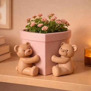Puede incluir: Una maceta cuadrada rosa con un grupo de flores rosas, flanqueada por dos figuras de osos de peluche marrones. Los osos parecen abrazar la maceta. La maceta está sobre una estantería de madera.
