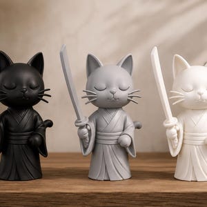 May include: Three cat figurines in black, gray, and white, each holding a sword. The cats are dressed in traditional Japanese attire with closed eyes, standing on a wooden surface. A bonsai tree is in the background.
