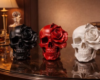 May include: Three decorative skull sculptures, each with a rose blooming from one side. The skulls are in black, red, and white. The sculptures are on a reflective surface.