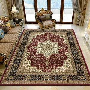 May include: A rectangular area rug with an ornate, traditional design. The rug features a central medallion in cream and burgundy, surrounded by a burgundy field and a black border with floral patterns. The rug is placed in a living room setting.