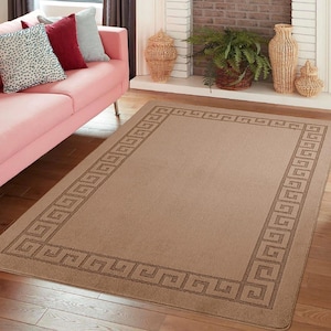 May include: A rectangular beige area rug with a Greek key border design. The rug is placed on a hardwood floor in a living room setting. The border is a darker shade of brown. The rug is a neutral color and would complement various decor styles.
