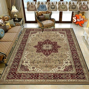 May include: A large rectangular area rug with an ornate floral design in beige, burgundy, and cream. The rug features a central medallion and a detailed border. Several smaller rugs are displayed above the main rug, showcasing different color variations.