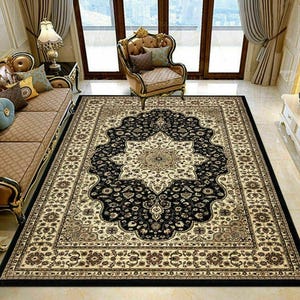 May include: A rectangular area rug with an ornate floral pattern. The rug features a central medallion in cream and gold, surrounded by a black field. The border is cream and brown with floral motifs. The rug is placed in a living room setting.
